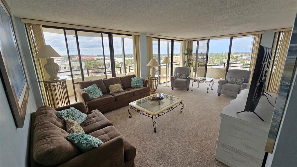 A living room with brown sofas, a glass coffee table, and floor-to-ceiling windows — 2900 N ATLANTIC AVENUE UNIT 305, DAYTONA BEACH, FL