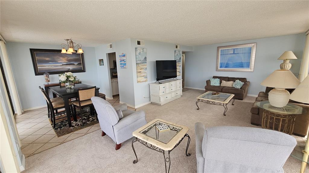 A living and dining area with carpeted floors, neutral walls, and a television on a dresser — 2900 N ATLANTIC AVENUE UNIT 305, DAYTONA BEACH, FL