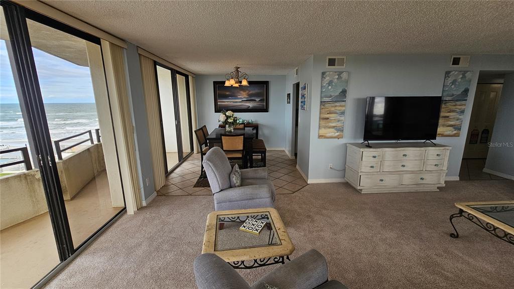 A living and dining area features carpeted floors, a balcony with ocean views, and furniture — 2900 N ATLANTIC AVENUE UNIT 305, DAYTONA BEACH, FL
