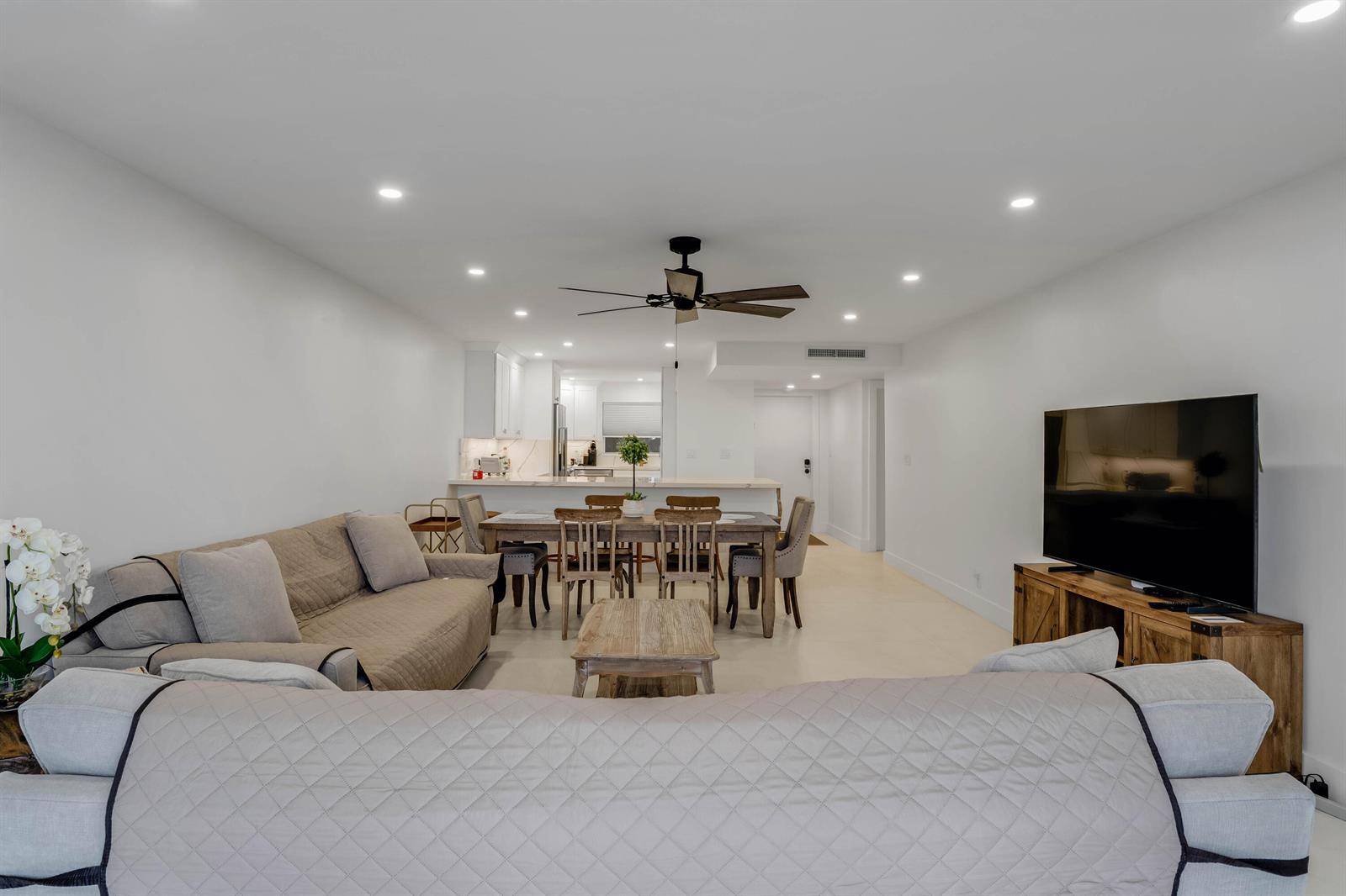 An open-concept living and dining area features white walls, recessed lighting, and neutral furniture — 401 Briny Avenue # 315, Pompano Beach FL 33062, POMPANO BEACH, FL