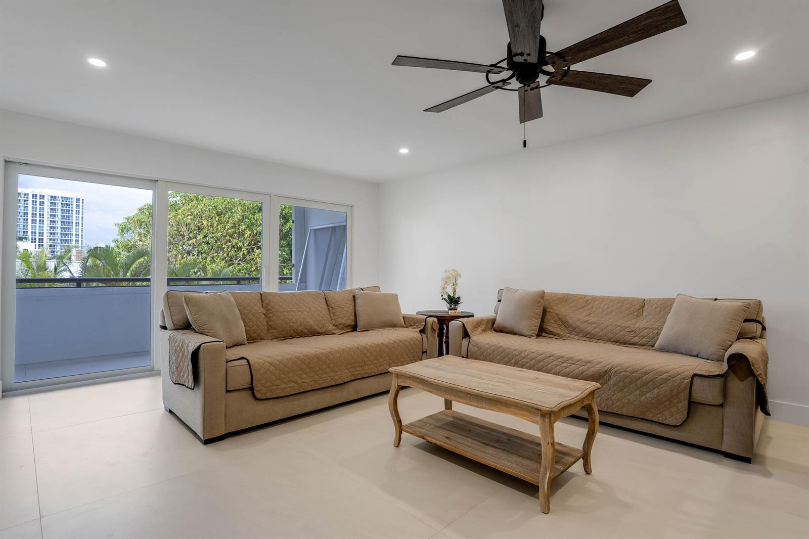 A living room features two tan sofas, a wooden coffee table, and a sliding glass door — 401 Briny Avenue # 315, Pompano Beach FL 33062, POMPANO BEACH, FL
