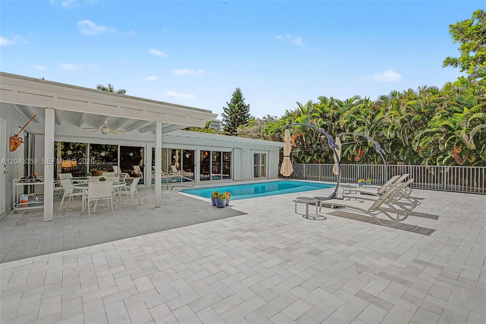 A patio with a swimming pool, outdoor dining area, and lounge chairs under a pergola — 340 Atlantic Rd, Key Biscayne FL 33149, KEY BISCAYNE, FL