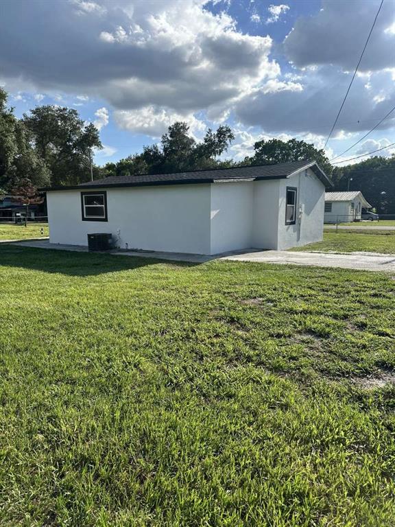 A white, single-story house with a dark roof sits on a grassy lot — 3329 LYNN DRIVE, LAKELAND, FL