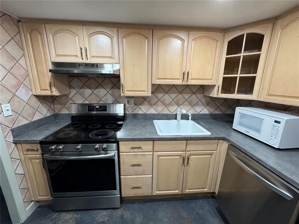 A kitchen features light wood cabinets, a stainless steel stove, and a white sink — 400 E COLONIAL DRIVE UNIT 108, ORLANDO, FL