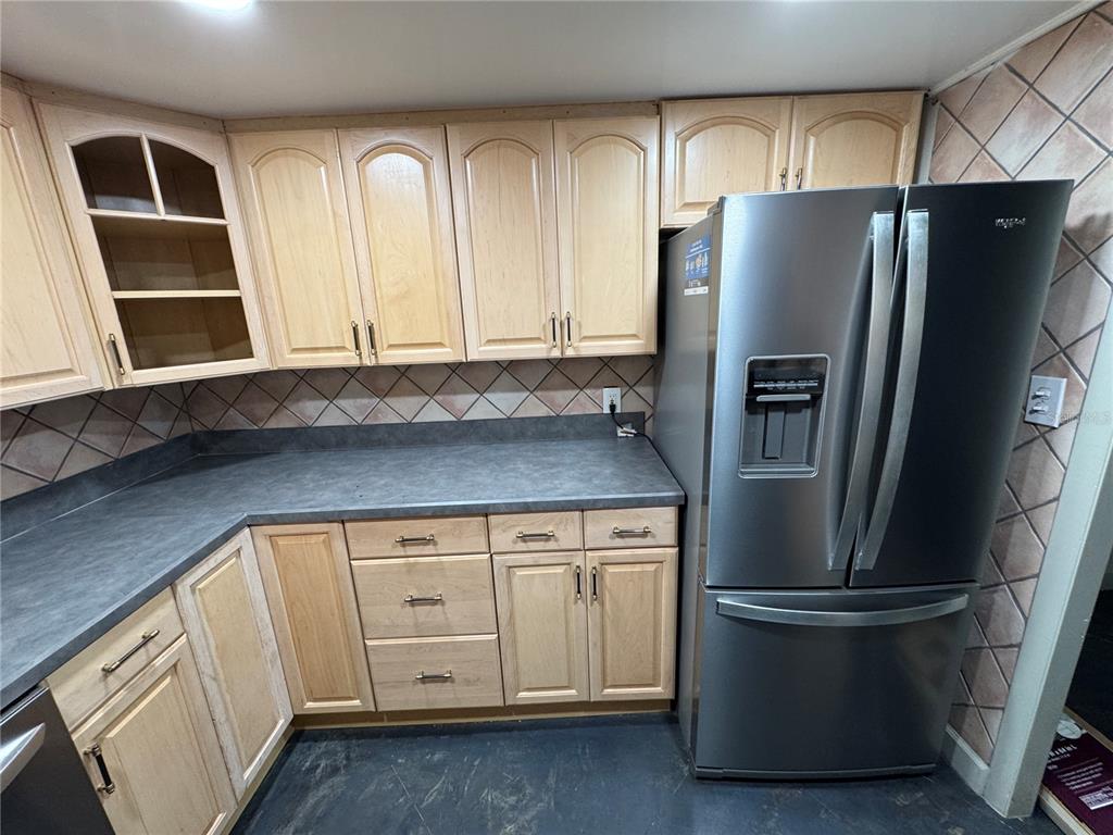 A kitchen features light wood cabinets, dark gray countertops, and a stainless steel refrigerator — 400 E COLONIAL DRIVE UNIT 108, ORLANDO, FL