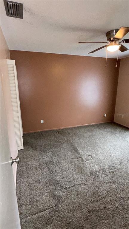 A bedroom with brown walls, gray carpet, a ceiling fan, and a white louvered closet door — 7309 ELEANOR CIRCLE UNIT 7309, SARASOTA, FL