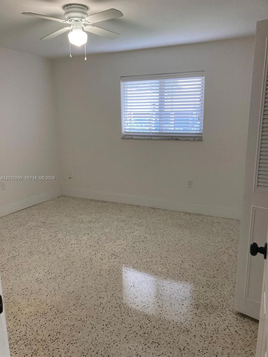 An empty bedroom features white walls, a ceiling fan, and light-colored speckled flooring — 12020 NE 12th Ct # 12020, Biscayne Park FL 33161, BISCAYNE PARK, FL