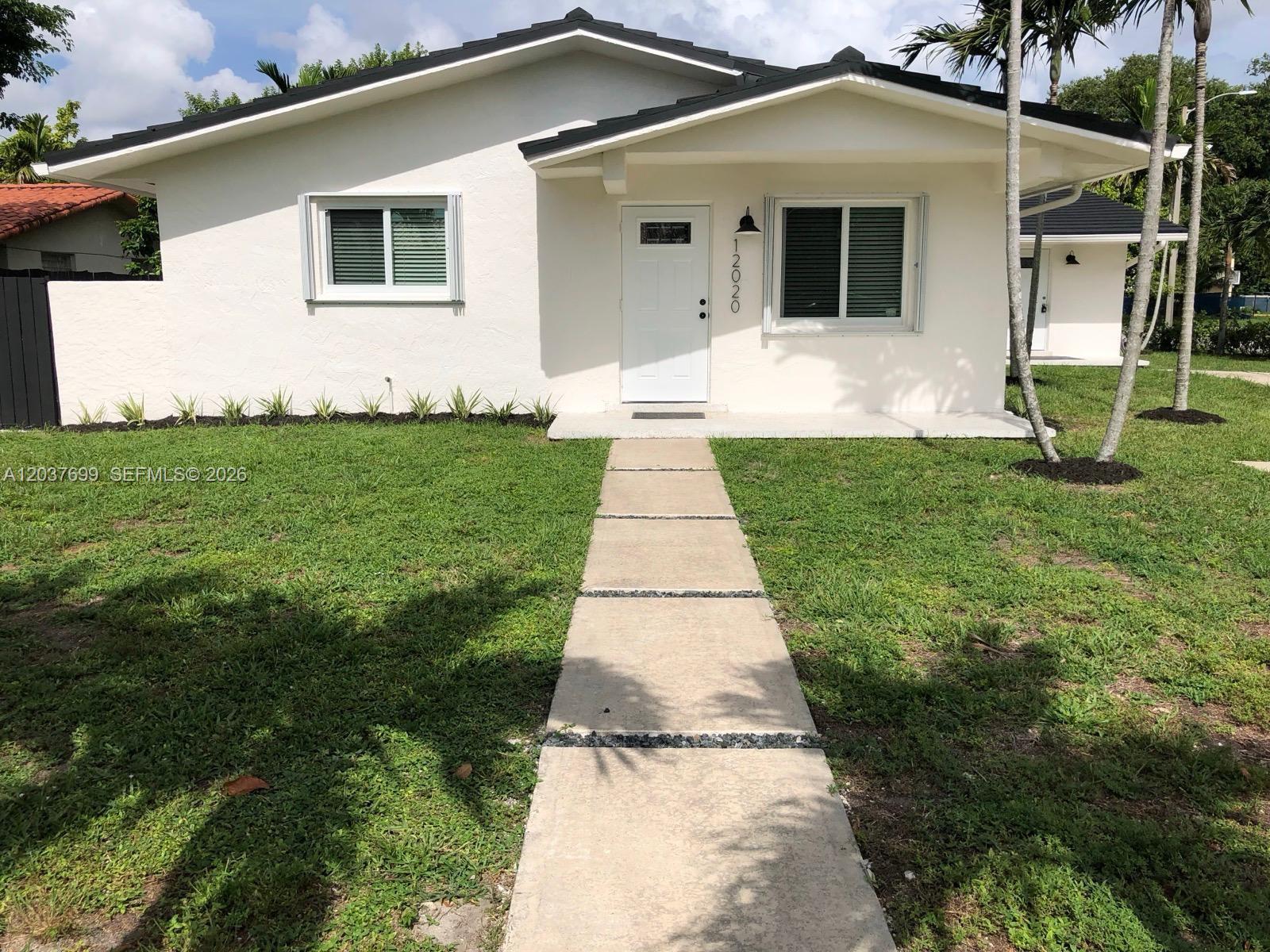 A single-story white house with a dark roof and a concrete walkway leading to the entrance — 12020 NE 12th Ct # 12020, Biscayne Park FL 33161, BISCAYNE PARK, FL
