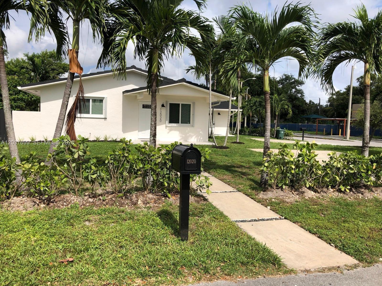 A white single-story house with a black roof, palm trees, and a front walkway — 12020 NE 12th Ct # 12020, Biscayne Park FL 33161, BISCAYNE PARK, FL