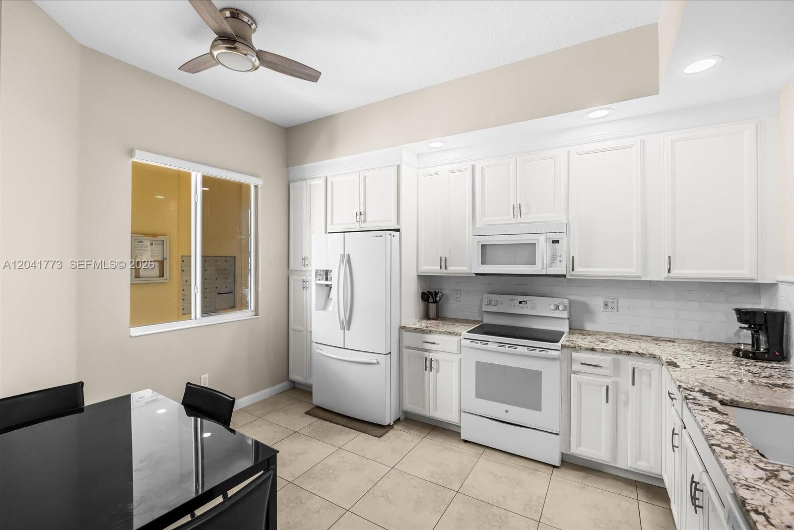 A kitchen features white cabinets, a white refrigerator, a white stove, and granite countertops — 38 E Harbour Isle Dr E # 104, Fort Pierce FL 34949, FORT PIERCE, FL