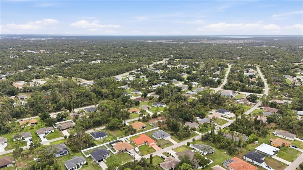 An aerial view shows a suburban neighborhood with single-family homes surrounded by dense trees — 4746 GLOBE TERRACE, NORTH PORT, FL