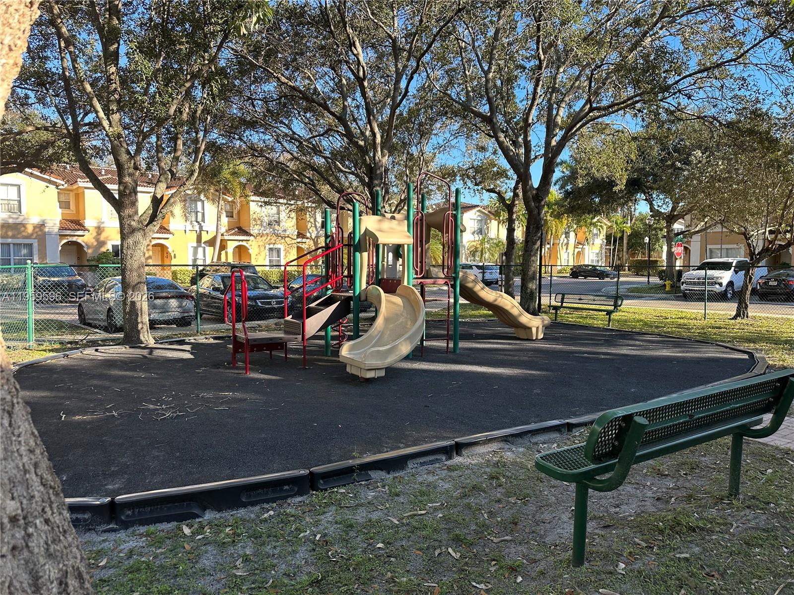 A playground with slides and a bench sits in front of multi-story residential buildings — 12811 SW 30th St # 110, Miramar FL 33027, MIRAMAR, FL