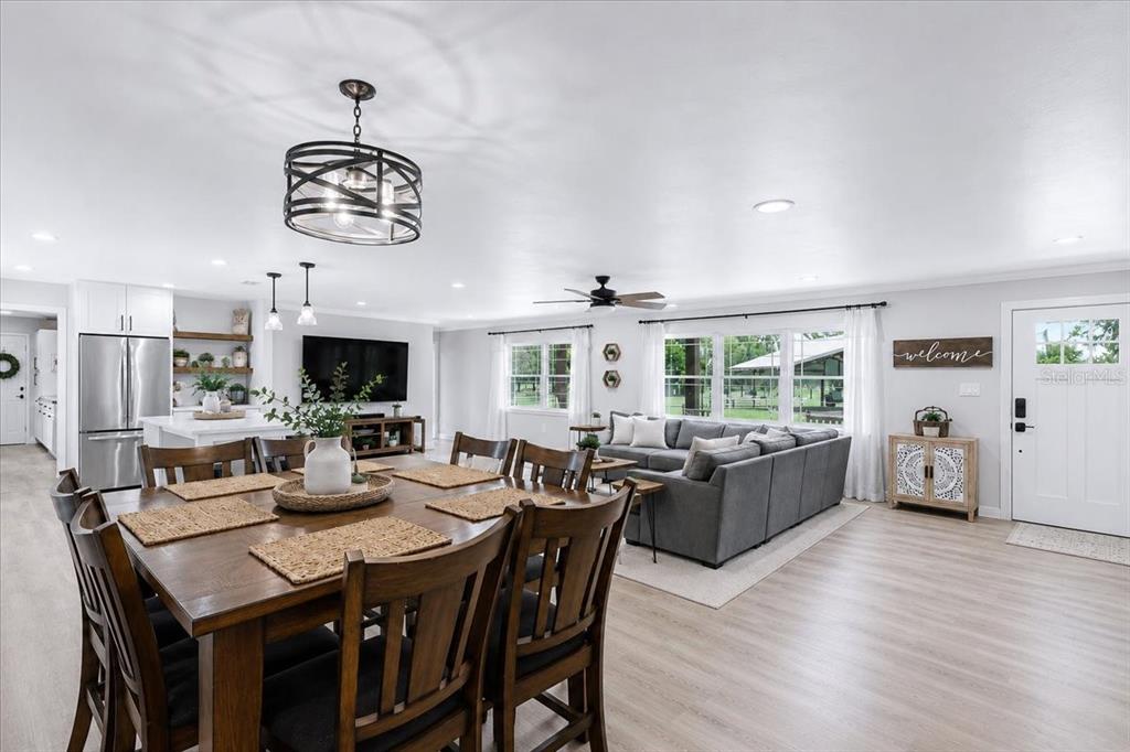 An open-concept living and dining area features wood flooring, a large sectional, and a chandelier — 3201 NW 202 STREET, NEWBERRY, FL