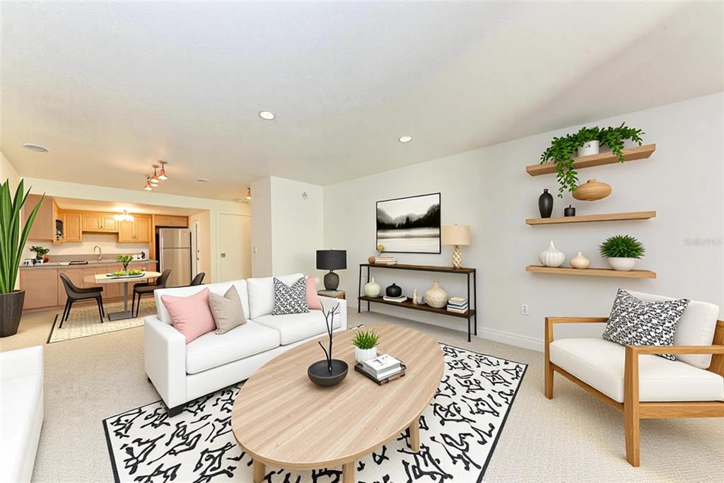 A living room with a white sofa, oval coffee table, and floating shelves on the wall — 3411 CLARK ROAD UNIT 212, SARASOTA, FL