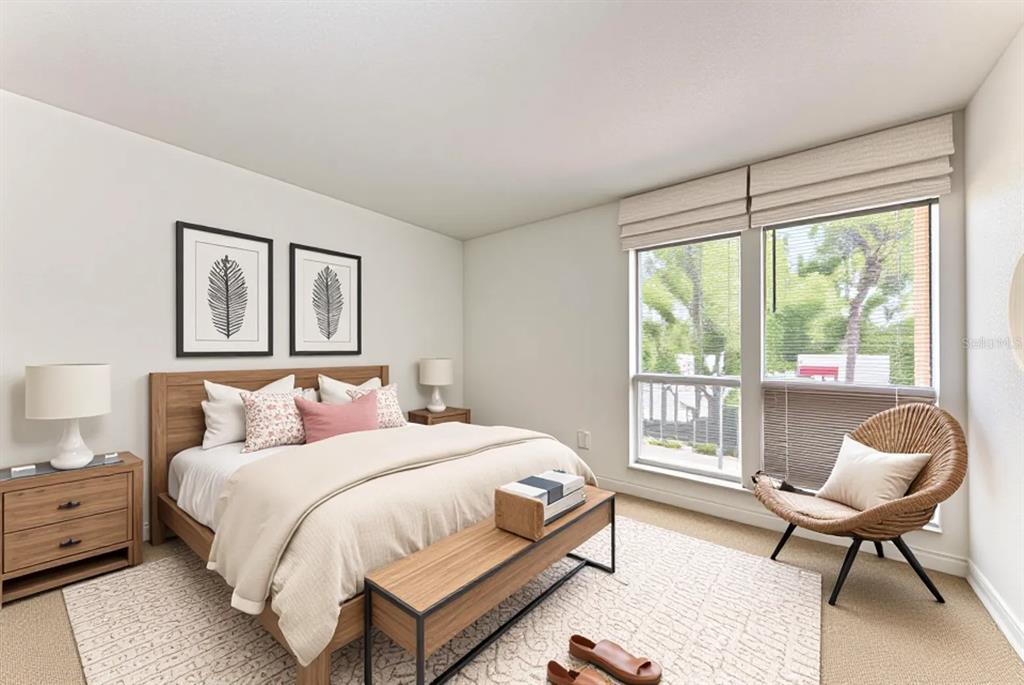 A bedroom features a wooden bed frame, a bench, a wicker chair, and large windows — 3411 CLARK ROAD UNIT 212, SARASOTA, FL