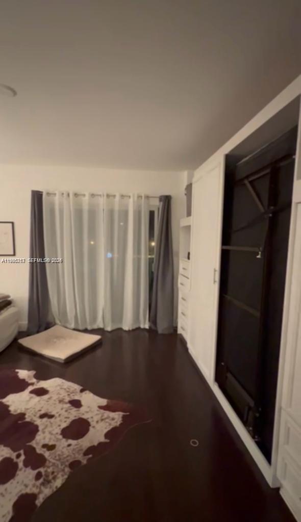 A bedroom features dark wood flooring, a wall-mounted Murphy bed, and floor-to-ceiling window curtains — 2740 SW 28th Ter # 503, Miami FL 33133, MIAMI, FL