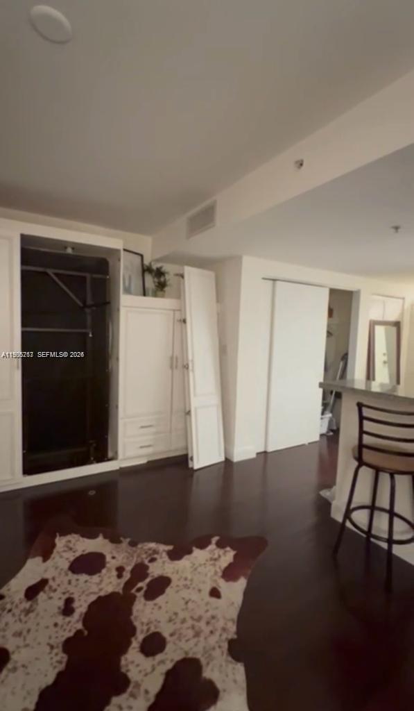 A room features dark wood flooring, a white built-in wall unit, and a bar stool — 2740 SW 28th Ter # 503, Miami FL 33133, MIAMI, FL
