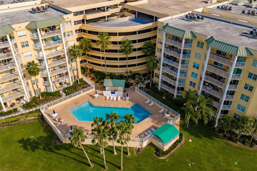 An aerial view shows a swimming pool surrounded by palm trees and multi-story apartment buildings — 4650 LINKS VILLAGE DRIVE UNIT D501, PONCE INLET, FL
