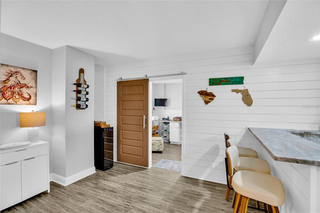A basement room features a bar, shiplap wall, wine cooler, and a sliding barn door — 4650 LINKS VILLAGE DRIVE UNIT D501, PONCE INLET, FL