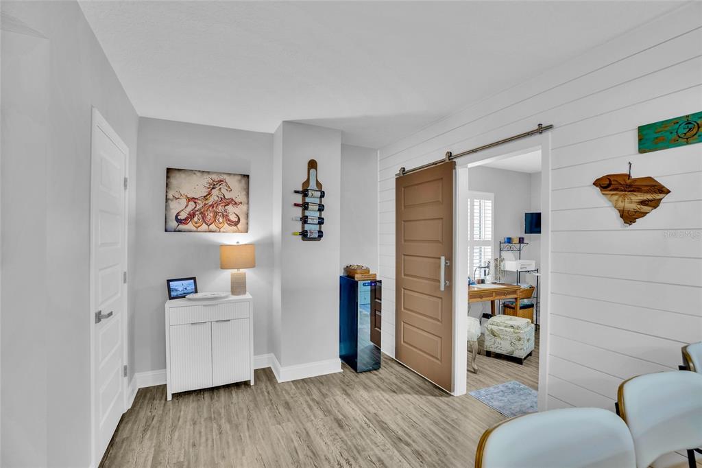 A room with light gray walls, wood-look flooring, a white cabinet, and a sliding barn door — 4650 LINKS VILLAGE DRIVE UNIT D501, PONCE INLET, FL