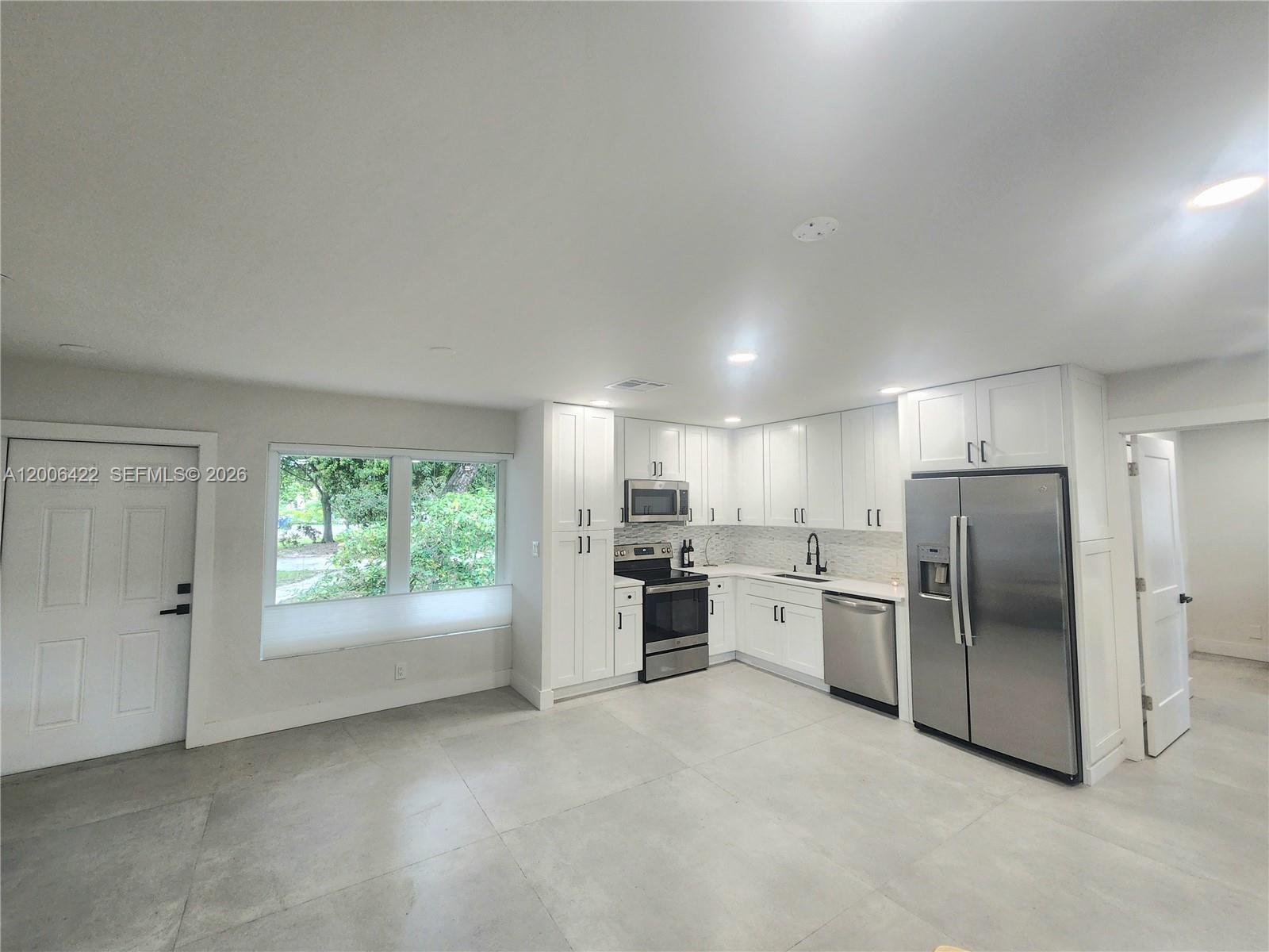 A modern kitchen features white cabinets, stainless steel appliances, and light tile flooring — 141 NE 30th St, Wilton Manors FL 33334, WILTON MANORS, FL