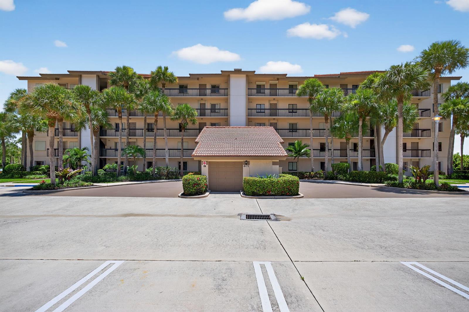A multi-story apartment building with balconies stands behind a small detached garage structure — 401 Ocean Bluffs Boulevard # 205, Jupiter FL 33477, JUPITER, FL