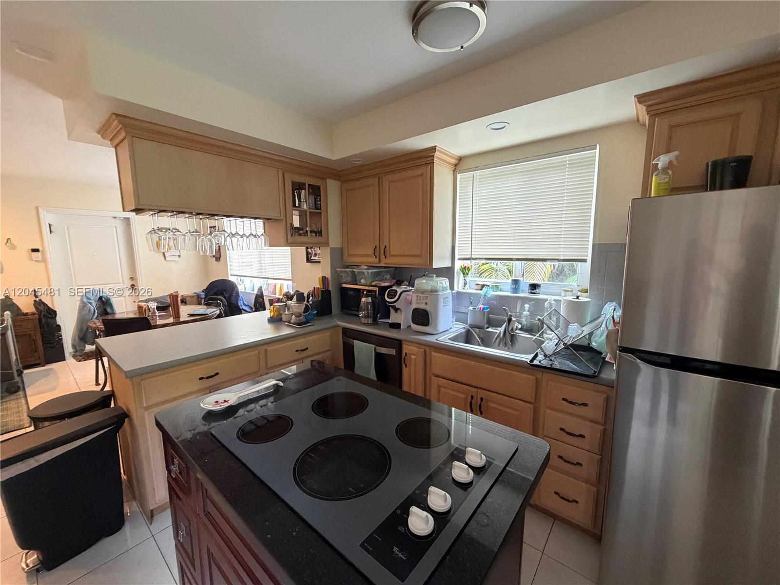 A kitchen features light wood cabinets, a black island cooktop, and stainless steel appliances — 2862 SW 38 Ave, Miami FL 33134, MIAMI, FL