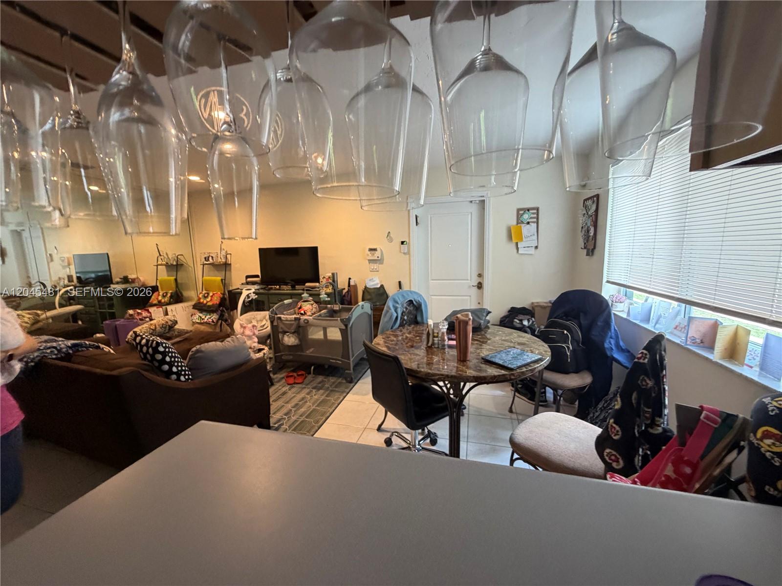 A living and dining area features hanging wine glasses, a round table, and a playpen — 2862 SW 38 Ave, Miami FL 33134, MIAMI, FL