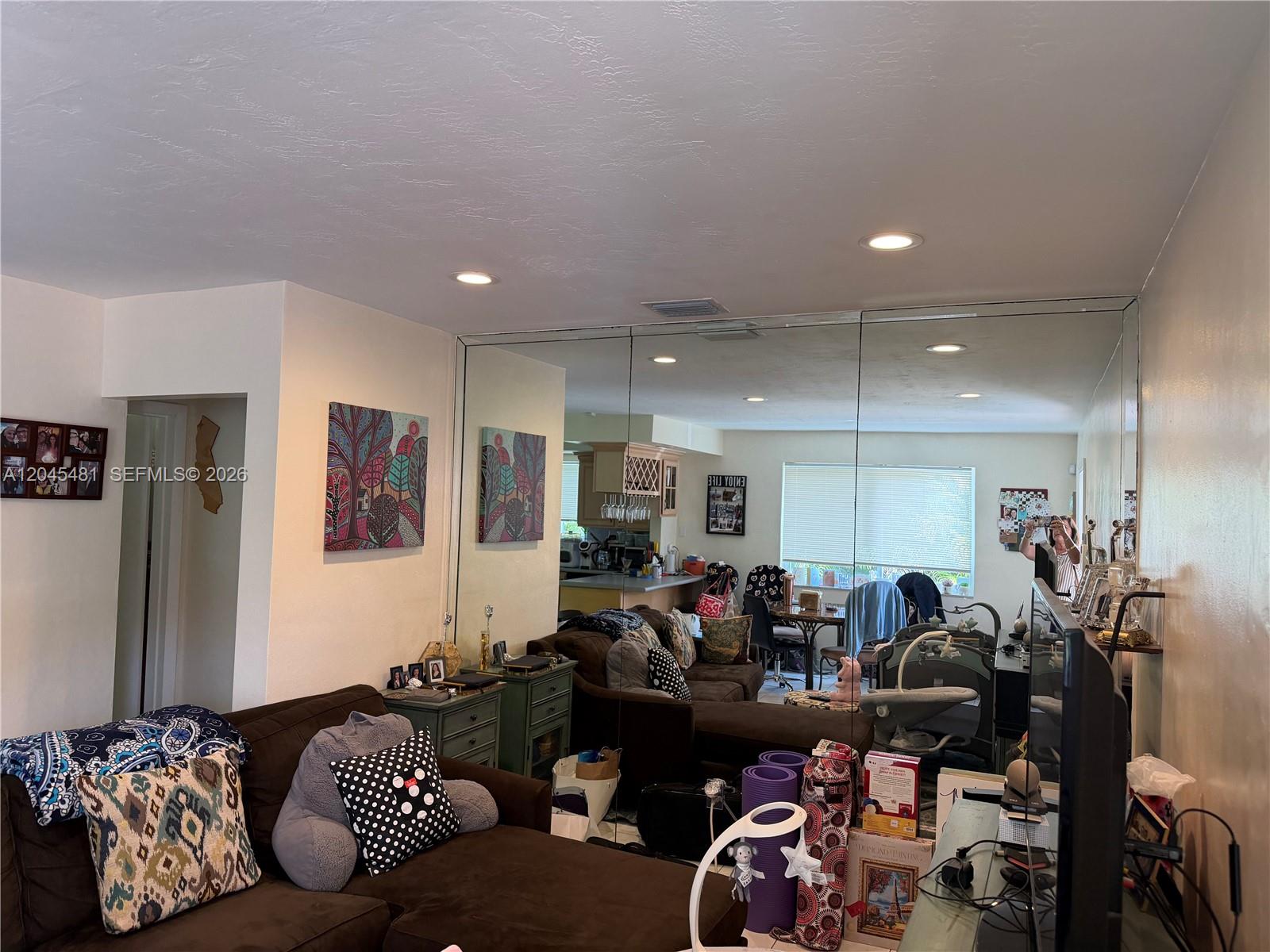 A living room features a large mirrored wall, a brown sectional sofa, and neutral walls — 2862 SW 38 Ave, Miami FL 33134, MIAMI, FL