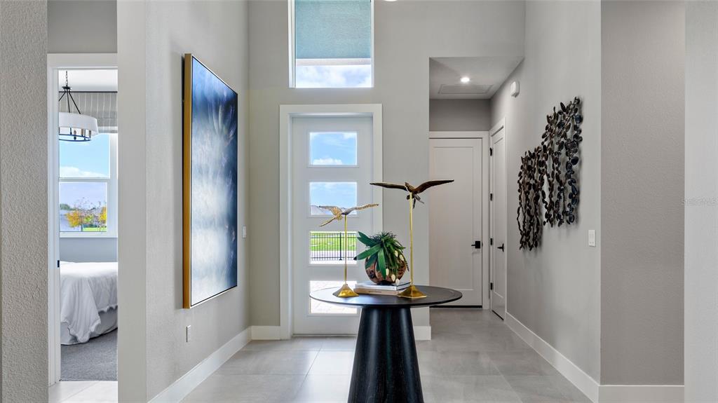 A bright entryway features a tall front door, a round pedestal table, and modern decor — 1104 LILIANA DRIVE, DELAND, FL