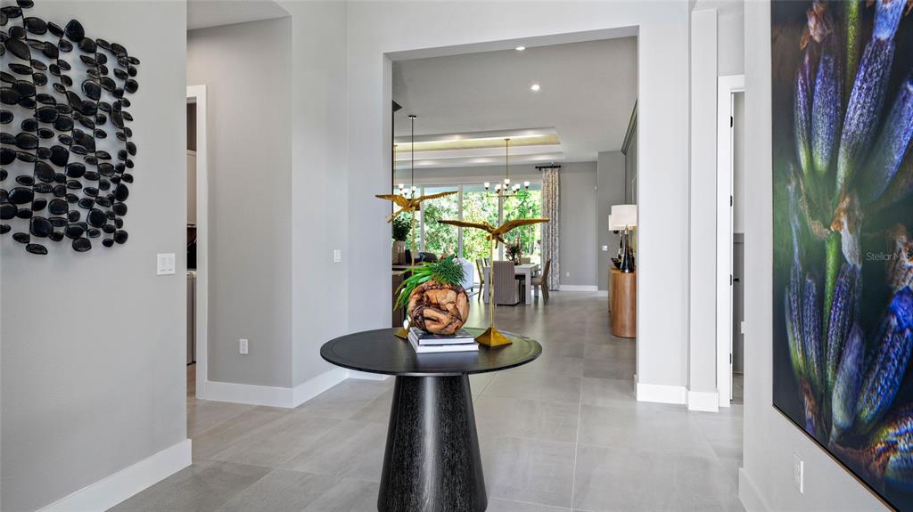 A modern entryway features a round pedestal table, wall art, and a view into a dining area — 1104 LILIANA DRIVE, DELAND, FL