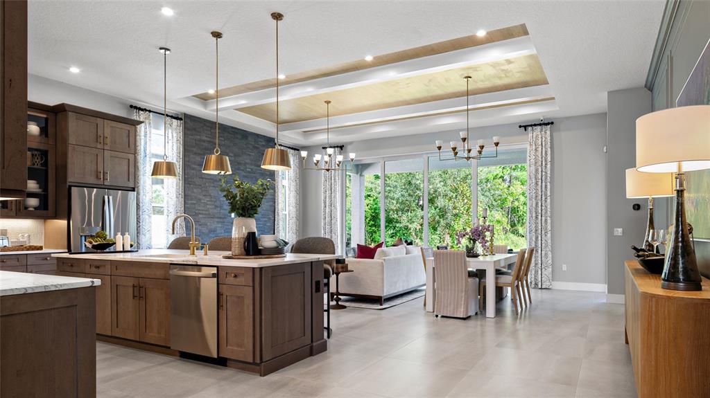 A modern open-concept kitchen and dining area features wood cabinetry, pendant lighting, and tray ceilings — 1104 LILIANA DRIVE, DELAND, FL