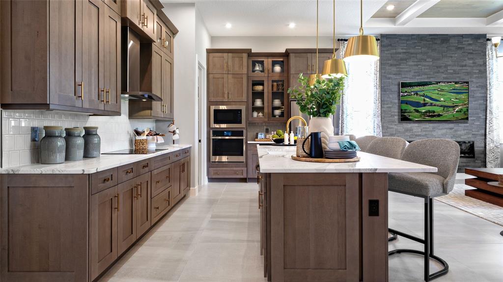 A modern kitchen features dark wood cabinets, a marble-topped island, and a stone fireplace wall — 1104 LILIANA DRIVE, DELAND, FL