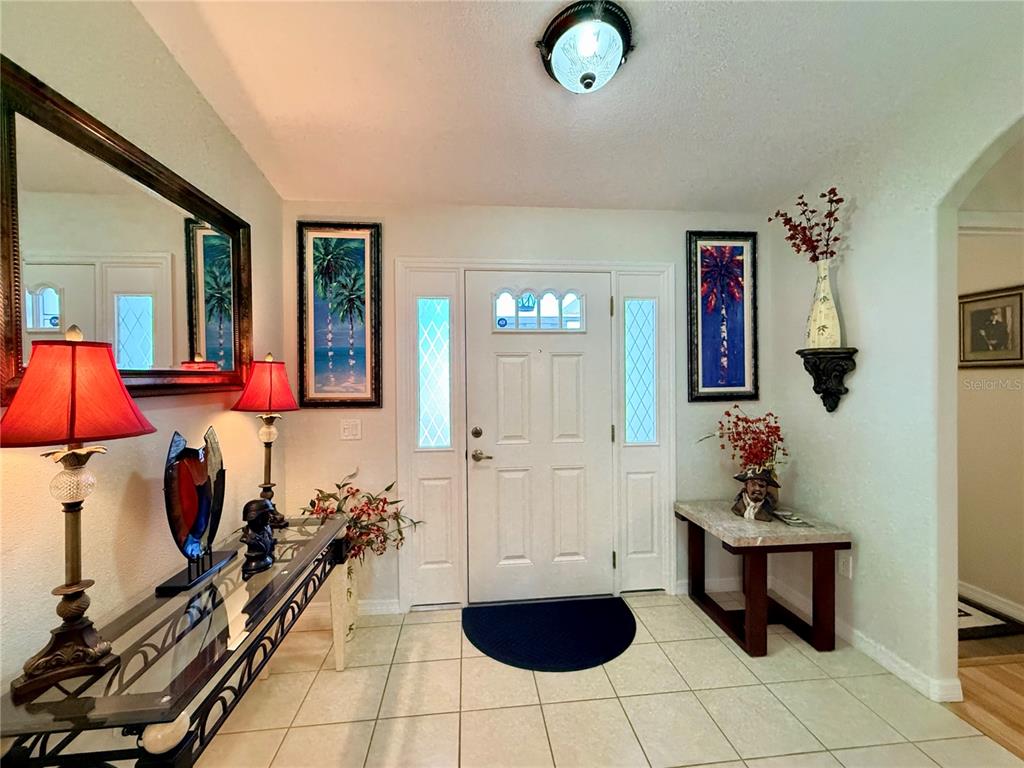 An entryway features a white front door with sidelights, tiled floors, and decorative console tables — 16304 SW 12TH TERRACE, OCALA, FL