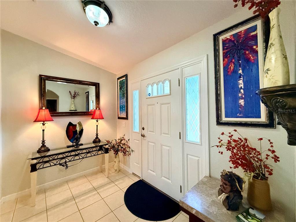 An entryway features a white front door, tiled floors, a console table, and wall art — 16304 SW 12TH TERRACE, OCALA, FL