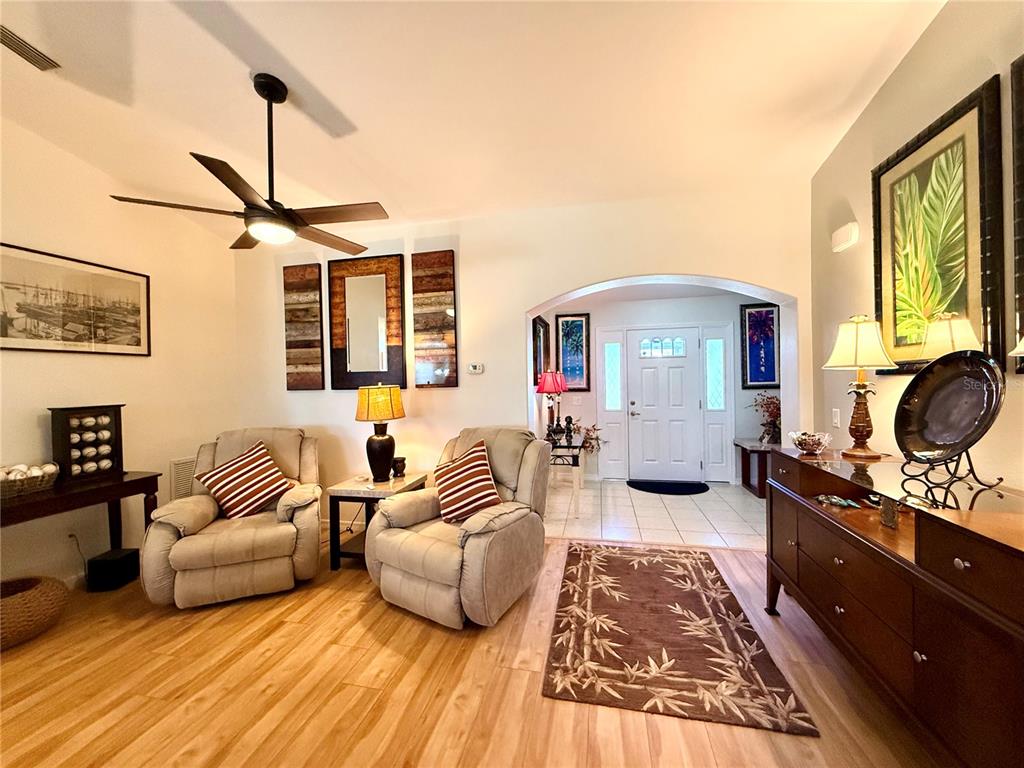 A living room features light wood flooring, two beige armchairs, and an arched entryway — 16304 SW 12TH TERRACE, OCALA, FL