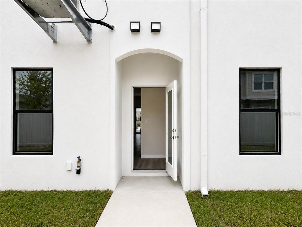A white exterior wall features a central open door flanked by two black-framed windows — 4341 CAMBIO GARDENS COURT, TAMPA, FL