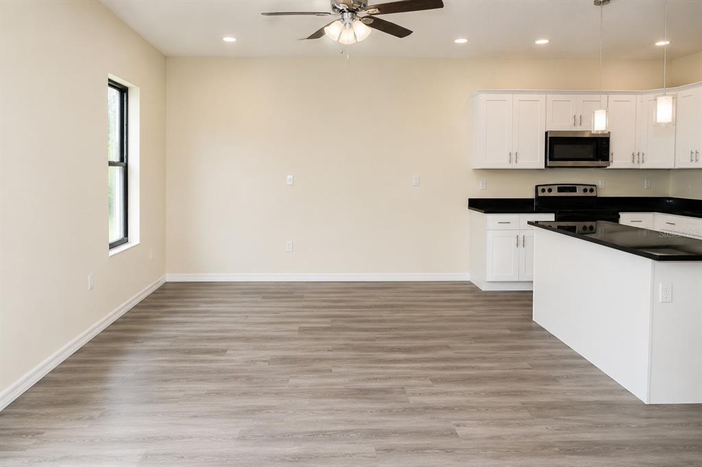 A bright dining area with wood-look flooring opens to a kitchen with white cabinets — 4341 CAMBIO GARDENS COURT, TAMPA, FL