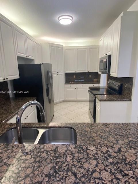 A kitchen features white cabinets, dark granite countertops, stainless steel appliances, and tile flooring — 10720 NW 66th ST # 503, Doral FL 33178, DORAL, FL