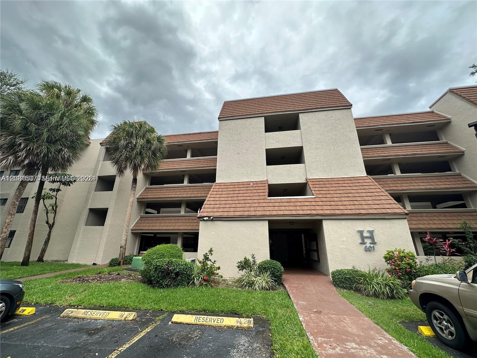 A multi-story apartment building exterior features tan stucco walls, brown tiled roofs, and palm trees — 601 Ives Dairy Rd # 8, Miami FL 33179, MIAMI, FL