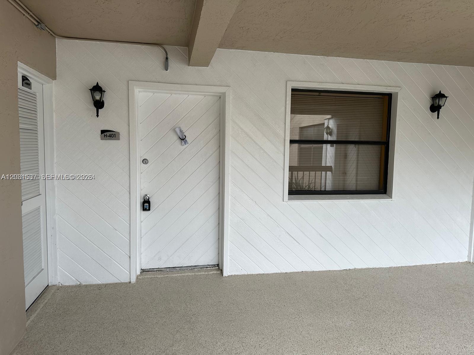 A white exterior door with a diagonal pattern and a window on a textured wall — 601 Ives Dairy Rd # 8, Miami FL 33179, MIAMI, FL