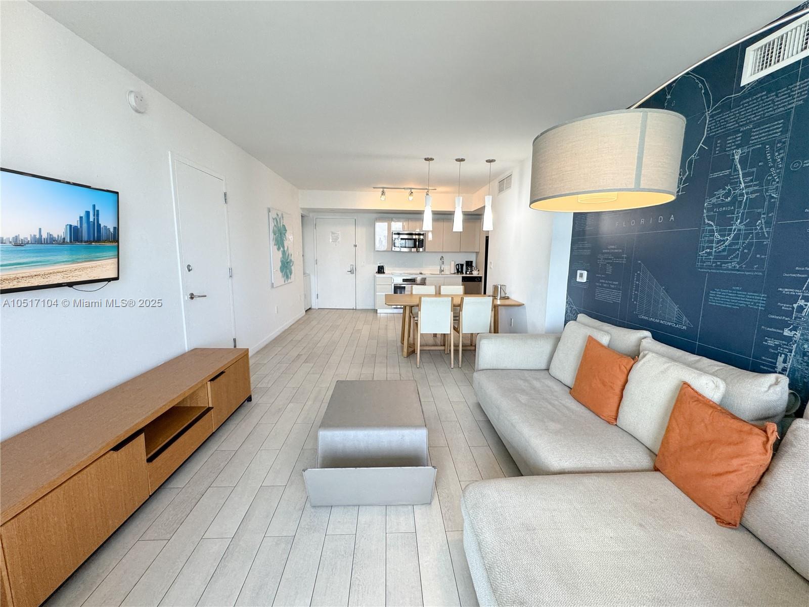 A living room with a sofa, television, and dining area features light wood-look flooring — 2602 E Hallandale Beach Blvd # 1708, Hallandale Beach FL 33009, HALLANDALE BEACH, FL