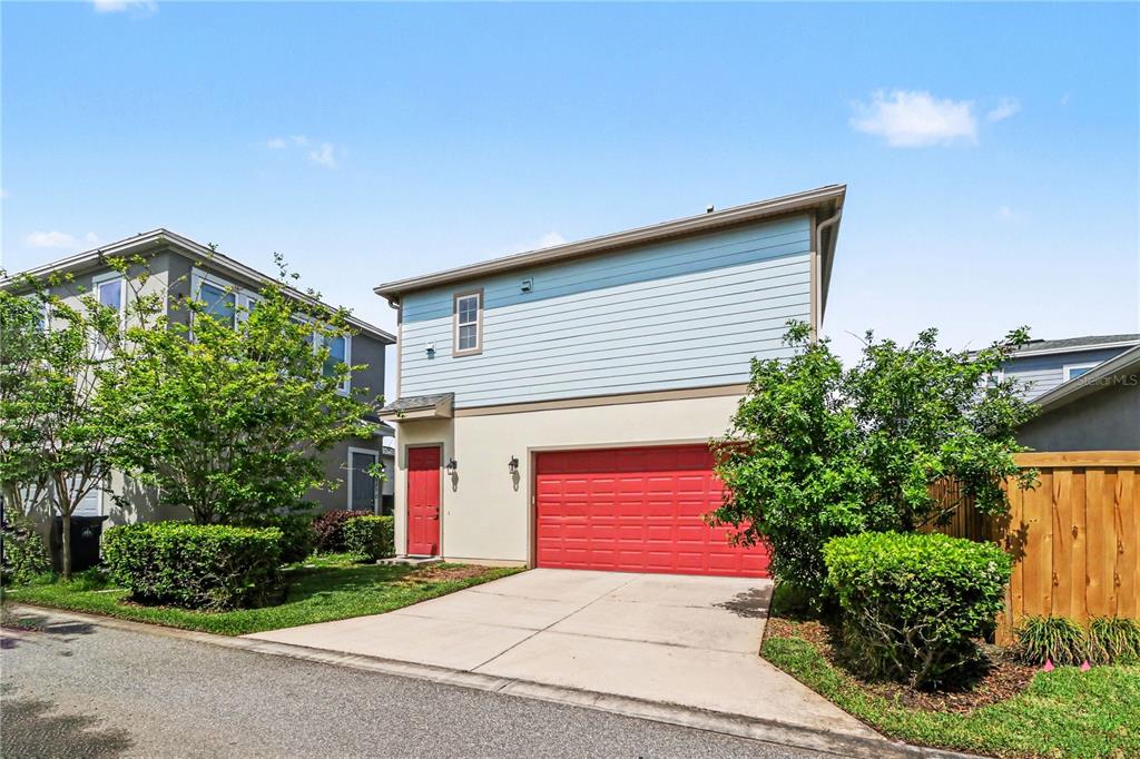 A two-story house with light blue siding, a red garage door, and a red front door — 8274 R NEMOURS PARKWAY, ORLANDO, FL