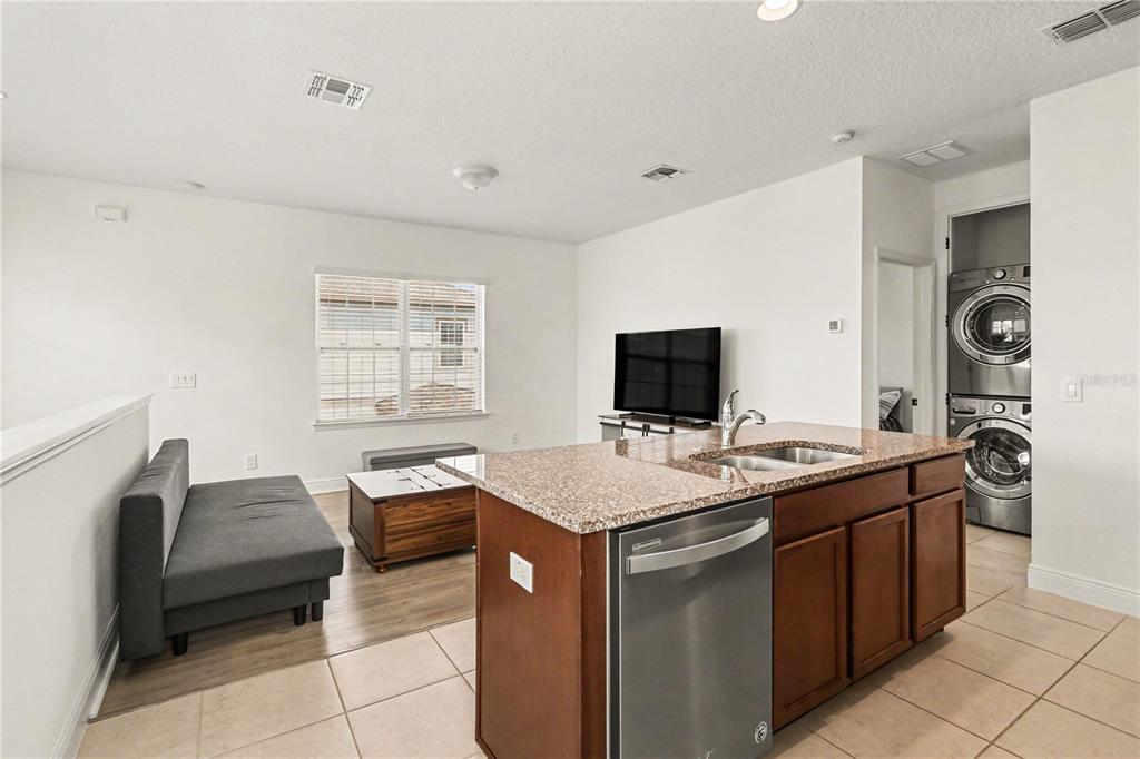 A kitchen island with a stainless steel dishwasher faces a living area with a sofa — 8274 R NEMOURS PARKWAY, ORLANDO, FL