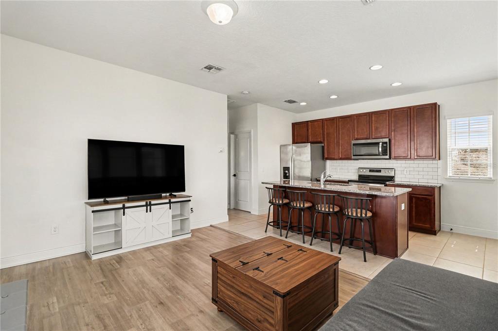 A living room with wood-look flooring flows into a kitchen featuring dark wood cabinets — 8274 R NEMOURS PARKWAY, ORLANDO, FL