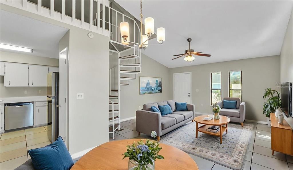A living room features a spiral staircase, a gray sofa, and a round coffee table — 236 VILLAGE CREST COURT, LAKELAND, FL