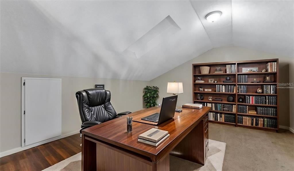 A home office features a wooden desk, a black leather chair, and a large bookshelf — 236 VILLAGE CREST COURT, LAKELAND, FL