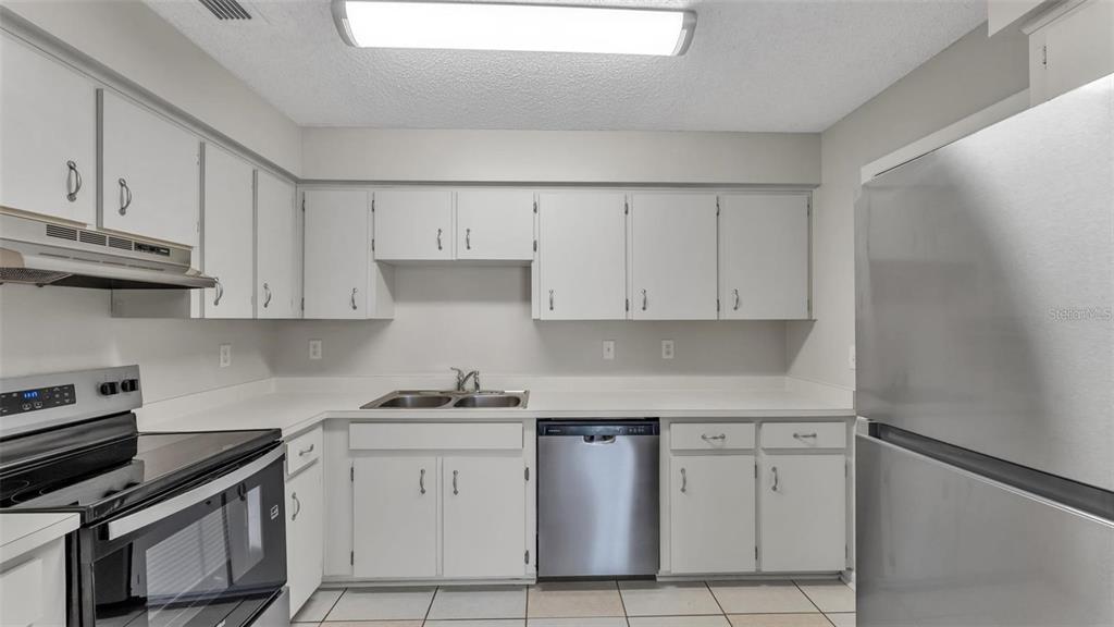 A kitchen with white cabinets, stainless steel appliances, and tile flooring — 236 VILLAGE CREST COURT, LAKELAND, FL