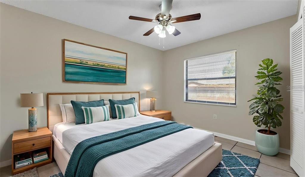 A bedroom features a queen bed with teal accents, a ceiling fan, and a potted plant — 236 VILLAGE CREST COURT, LAKELAND, FL