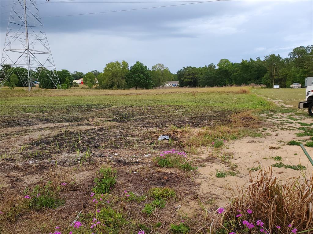 A large, flat, grassy lot features a tall electrical transmission tower on the left side — LOT 15 & 16 SE MARICAMP ROAD, OCALA, FL